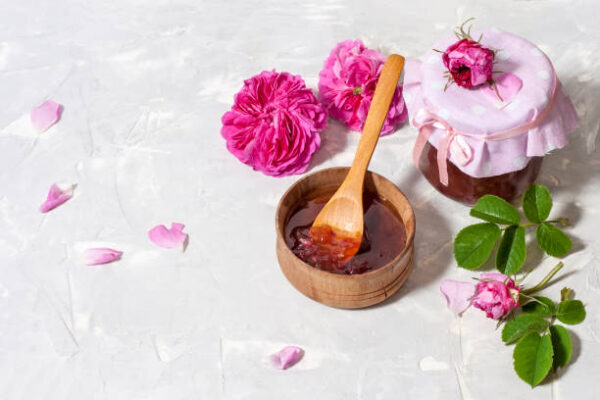 Homemade tea rose petal jam on a light table with copy space.