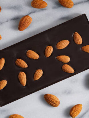 Top view of the dark chocolate with almonds on a white marble background