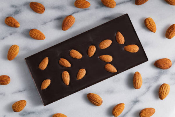 Top view of the dark chocolate with almonds on a white marble background